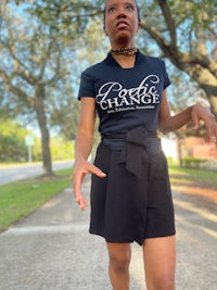 a woman in a black skirt and t - shirt walking down the street